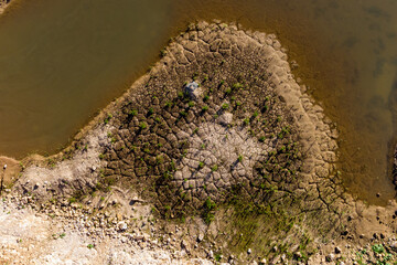 The shore of a reservoir with silt is cracked from drying out. Drying crack texture from above