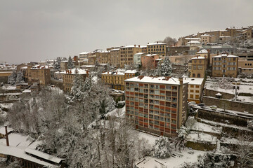 Aerial winter landscape of dense historic center of Thiers town in Puy-de-Dome department, Auvergne-Rhone-Alpes region in France. Rooftops of old buildings and narrow streets at snowfall