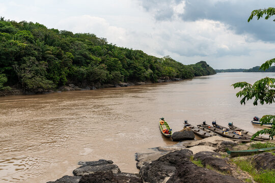 Rocks, amazonian river, boats and jungle in the area of colombian amazon, cloudy and green picture