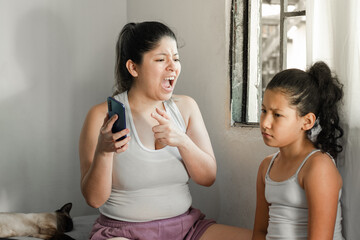 mother yelling and scolding her little daughter to put down her cell phone and go do her homework.