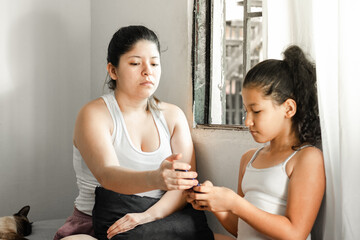 young mother about to take away her daughter's cell phone so that she would stop playing and do her...