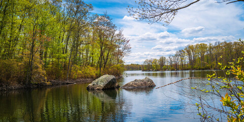 Lincoln Woods State Park and Olney Pond spring landscape with glacial rocks in the water and new sprouts on the trees near Providence, Rhodes Island, USA