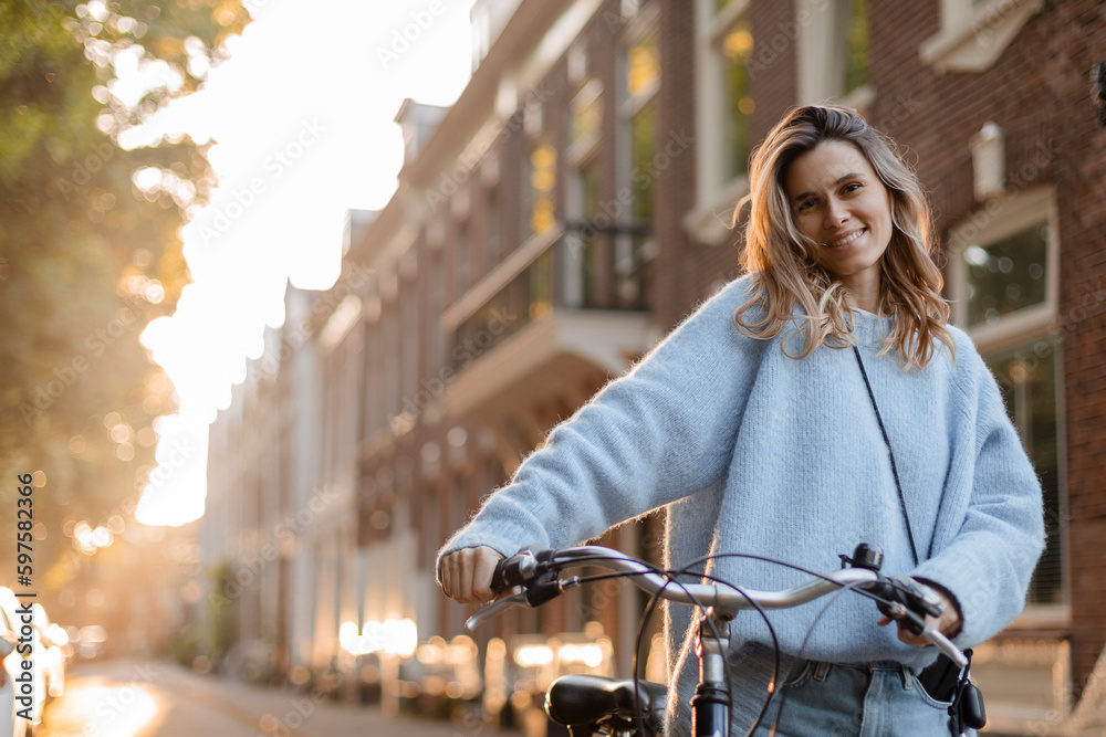 Wall mural portrait of a pretty young woman on bicycle in the city street, city transportation. outdoor fashion - Wall murals