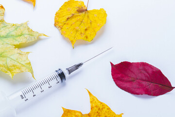 Autumn vaccination of population. Syringe in autumn leaves. Vaccination in autumn. New vaccine.