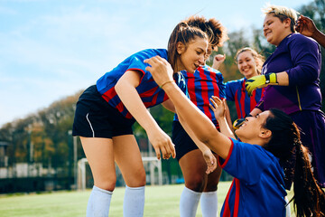 Obraz premium Team of female soccer players congratulates each other on their victory at stadium.