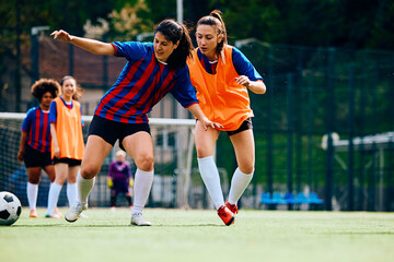 Young athletic women playing soccer on sports training at stadium.