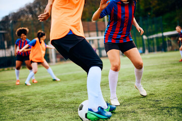 Fototapeta premium Unrecognizable athletic women practicing soccer on playing field.