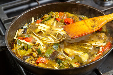 Frying pan with chopped stewed vegetables in sauce and spices with udon.