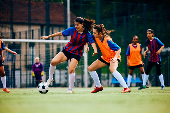 Fototapeta Young women practicing soccer on playing field.