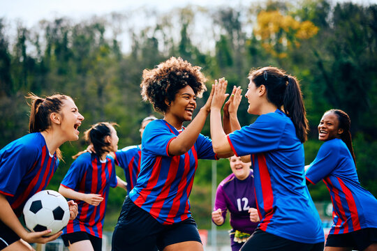 Fototapeta Happy women's soccer team celebrates victory after playing match at stadium.