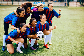 Cheerful women's soccer team screaming while celebrating winning championship.