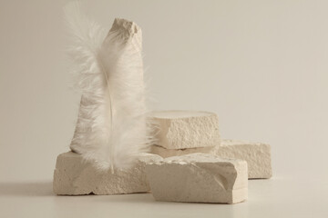 Texture stone platform, feather on light beige background. Minimal still life display product presentation scene.