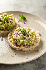 Healthy snack. Rice cake with avocado and tuna salad with red onion and parsley garnish.