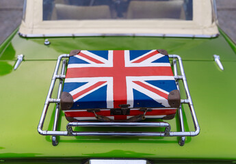 Suitcase with united kingdom flag on back of green oldtimer car