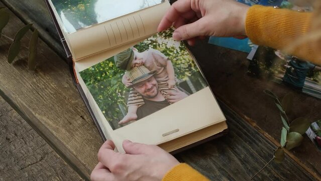 Father day concept. Female hands inserting printed photo of happy father and son into photo album.
