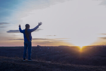 Fototapeta na wymiar A girl with raised hands on the background of the sky. Prayer. Glorification of God. Worshiping Jesus
