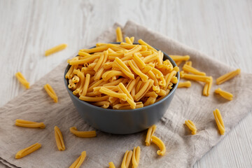 Homemade Raw Organic Caserecce Pasta in a Bowl on a white wooden background, side view.