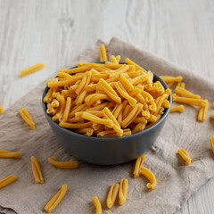 Homemade Raw Organic Caserecce Pasta in a Bowl on a white wooden background, side view.