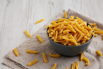 Homemade Raw Organic Caserecce Pasta in a Bowl on a white wooden background, side view. Copy space.