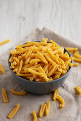 Homemade Raw Organic Caserecce Pasta in a Bowl on a white wooden background, side view. Copy space.