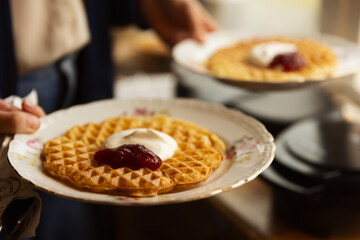 Hands holding two plates with waffles.