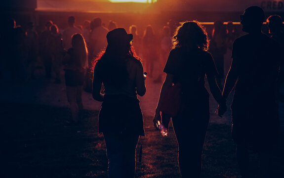 silhouettes of people walking at sunset festival