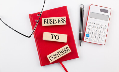 BUSINESS TO CUSTOMER text on wooden block on red notebook