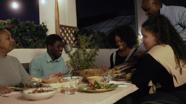 Family dinner: Happy African American people dining together at home terrace outdoors - Healthy food lifestyle