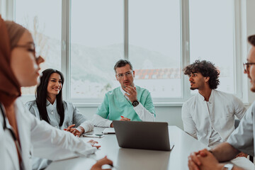 Fototapeta premium A group of multiethnic medical professionals including doctors, surgeons, and nurses are gathered in a hospital setting discussing patient care and using modern technology to address challenges in