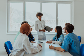 Obraz premium A group of multiethnic medical professionals including doctors, surgeons, and nurses are gathered in a hospital setting discussing patient care and using modern technology to address challenges in