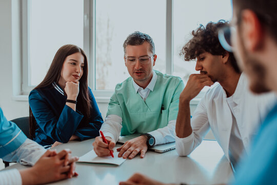 A group of multiethnic medical professionals including doctors, surgeons, and nurses are gathered in a hospital setting discussing patient care and using modern technology to address challenges in