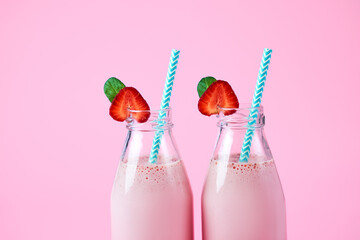 Close-up strawberry smoothie or milkshake in glass jar with berries on pink background. Summer drink