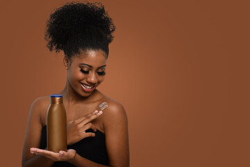 a woman applying moisturizing cream to her skin, smiling while holding a bottle demonstrating skin...