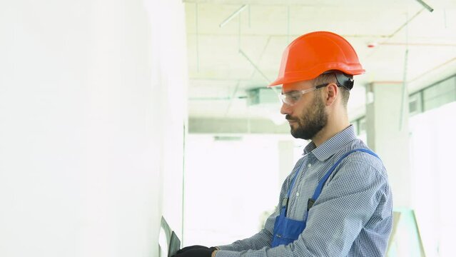 Plasterer construction worker, plastering the wall inside the building site
