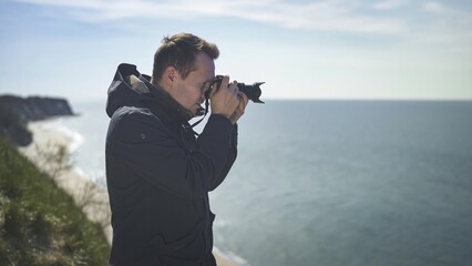 Obraz premium photographer on a cliff against the background of the sea