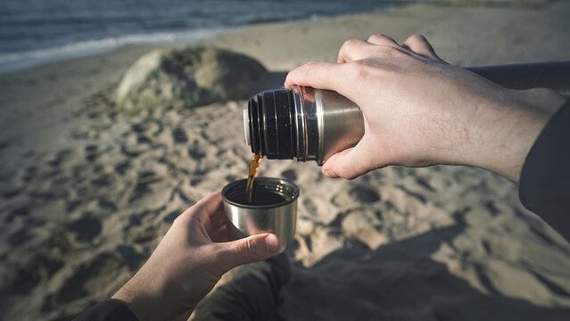 thermos with tea in the hands of the first person