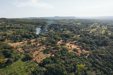 Obraz premium Aerial view of a rural area with some houses in between and smoke caused by people. Environmental pollution
