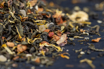 A large amount of dry green tea with pieces of fruit
