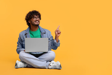 Smiling man with laptop on yellow background, space for text