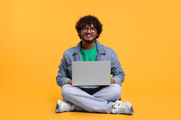 Smiling man with laptop on yellow background