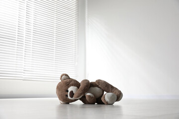 Cute lonely teddy bear on floor in empty room
