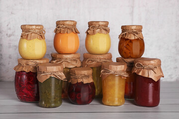 Many glass jars with different preserved products on wooden table