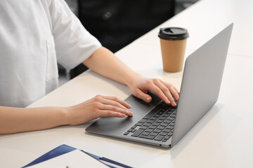 Woman working with laptop at white desk, closeup