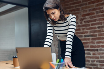 Architect engineer woman working with laptop while studying the blueprints in a modern office.