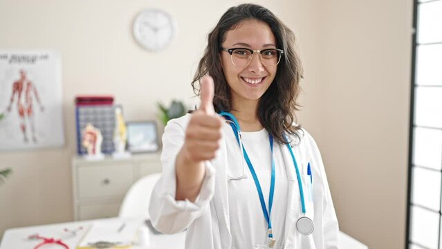Young beautiful hispanic woman doctor doing thumb up at clinic