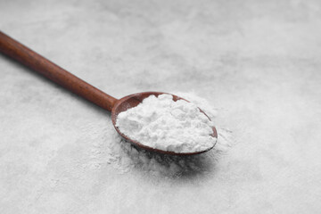 Spoon of starch on light gray table, closeup