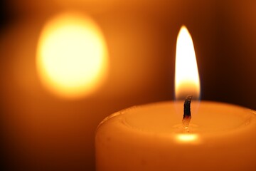 Burning candle on blurred background, closeup. Space for text