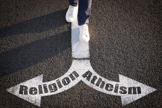 Choice between atheism and religion. Man walking towards drawn marks on road, closeup. Arrows with words pointing in opposite directions