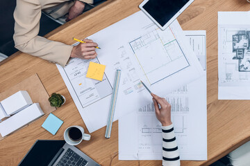 Hands of architects working with blueprints of their new design business in the office.