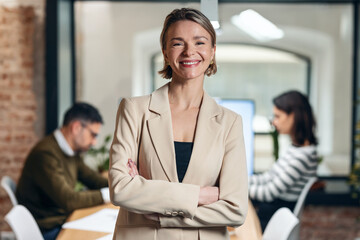 Mature designer woman working while looking at camera in a modern office at home.